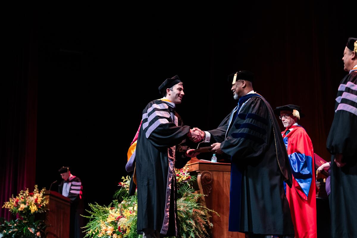Dean Mays and graduate shaking hands