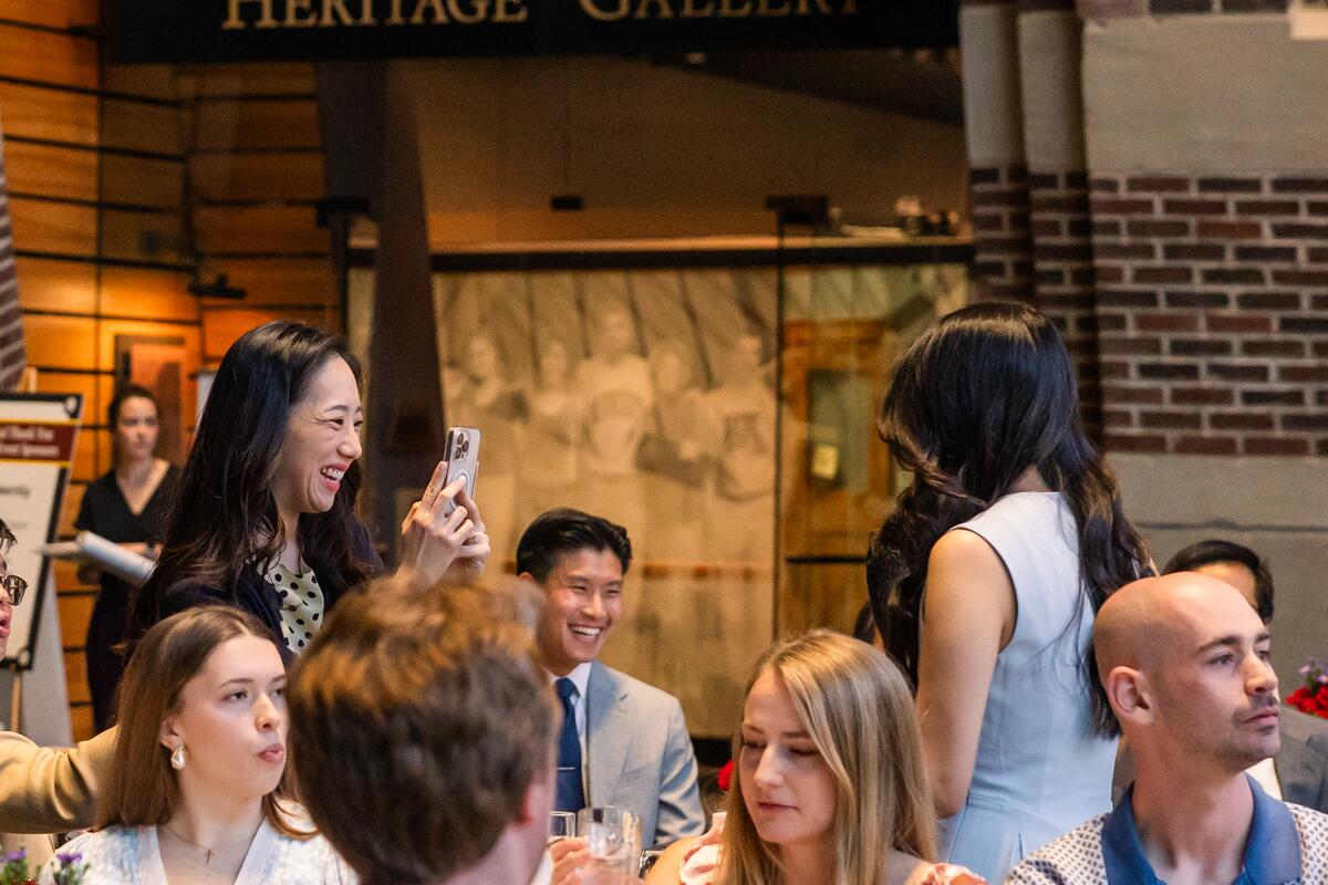 A parent takes a photo of a graduate receiving an award
