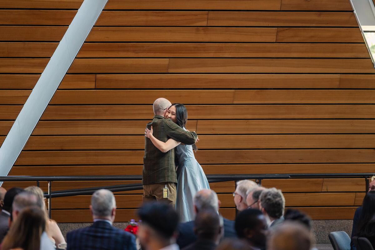 A student and an award presenter hug onstage