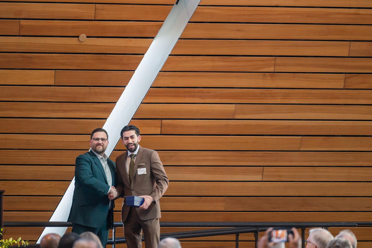 DDS student Alex Tabatabai receives an award onstage and smiles