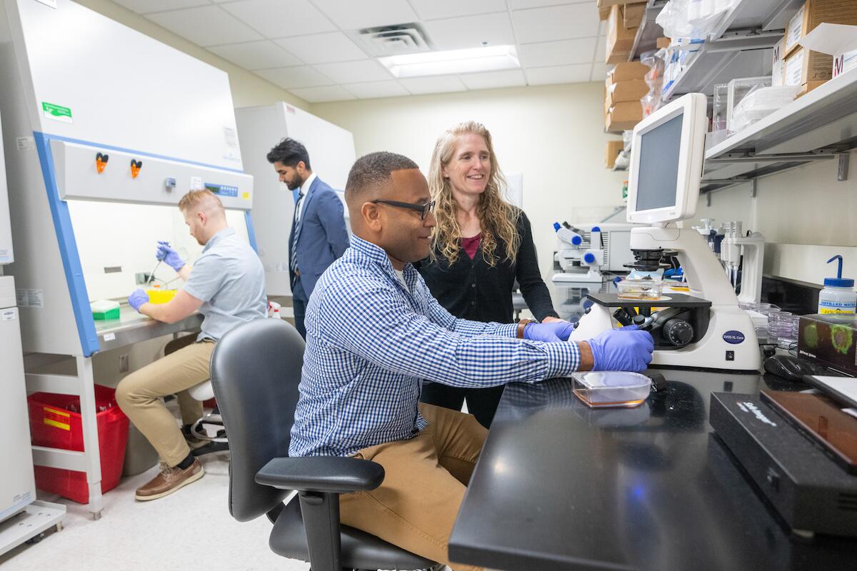 An oral biology faculty member consults a student on using a microscope