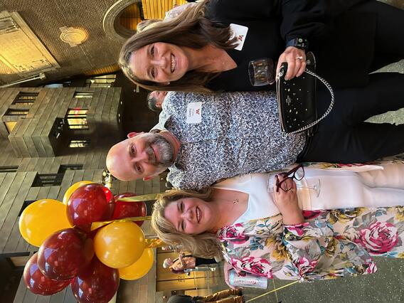 Three individuals smiling at reunion.