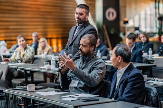 An attendee asks a question as other attendees look on