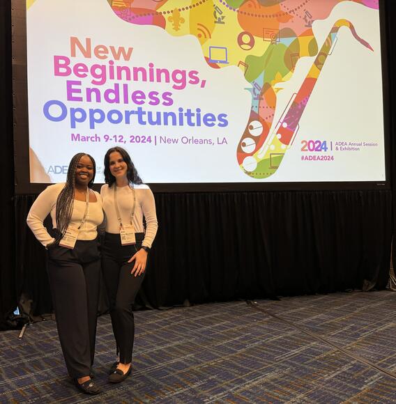 Sophie Chweya and another student pose in front of an ADEA sign