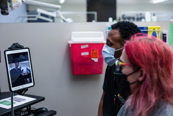 Two people on video call with other dentists on iPad.