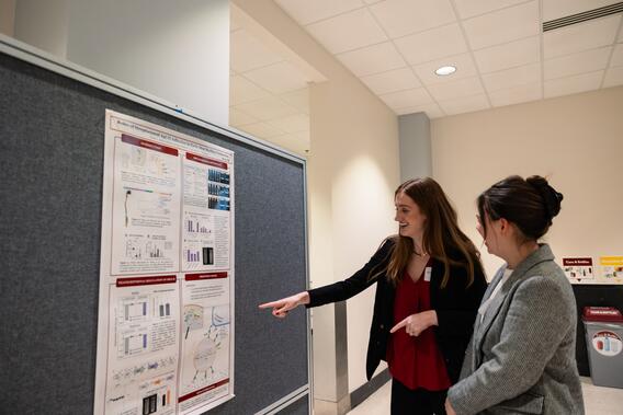 A student presents their research poster at research day