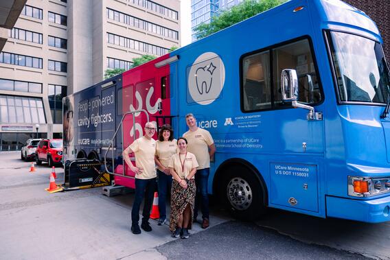 MDC parked outside Moos tower with 4 individuals standing in front of it.