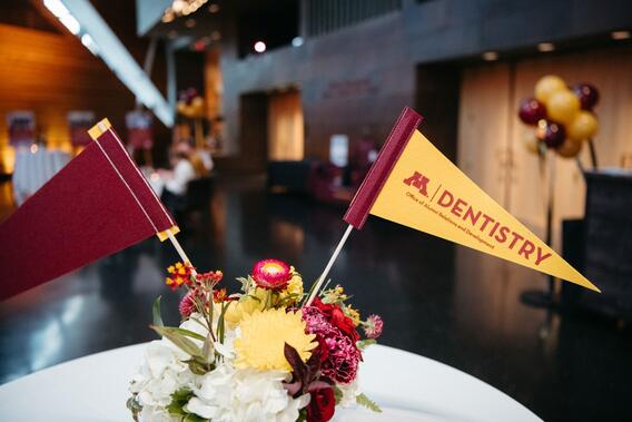 Maroon and gold pennants in a vase of flowers that read "Dentistry Office of Alumni Relations and Development"