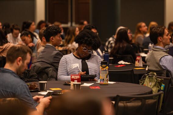 An attendee takes notes during a presentation at Research Day.
