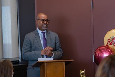Dean Keith Mays speaks and smiles behind a podium