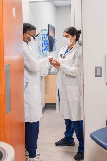 Two DDS students consult in the doorway of a clinical room at NorthPoint