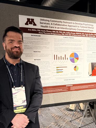 Eric Riklin poses in front of his poster