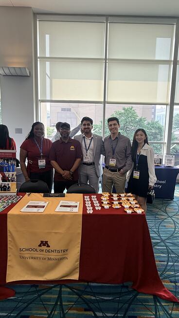 Joel Mixon and students pose behind a School of Dentistry booth at SNDA