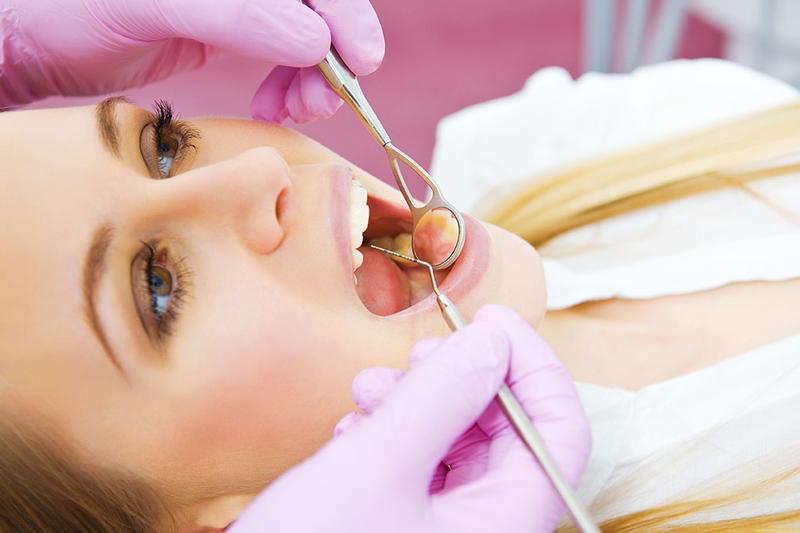 young female patient opens mouth during dental examinations