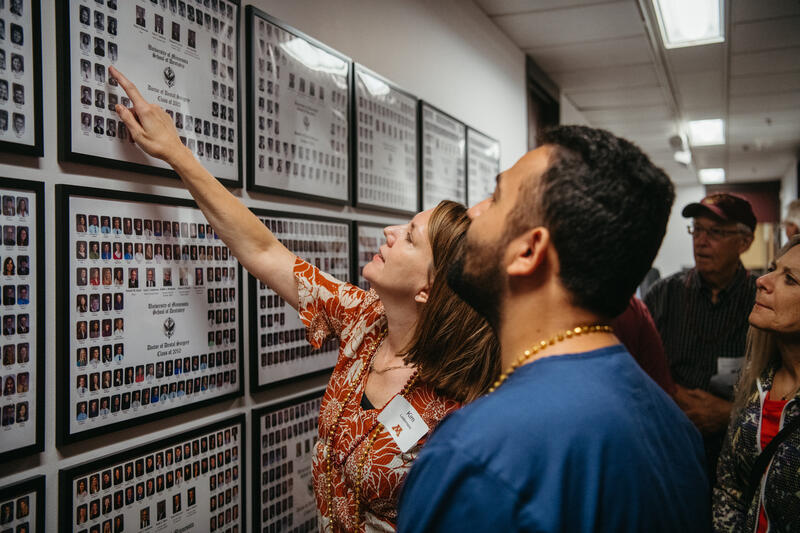 A dental school alumna points to her photo on a class composite