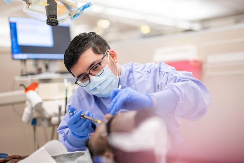 A dental student assists a patient in the clinic