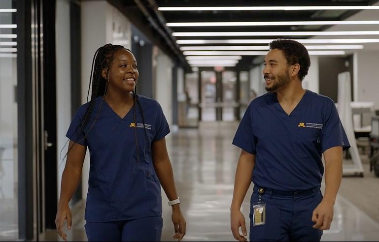 Two DDS students smile and walk down a hallway