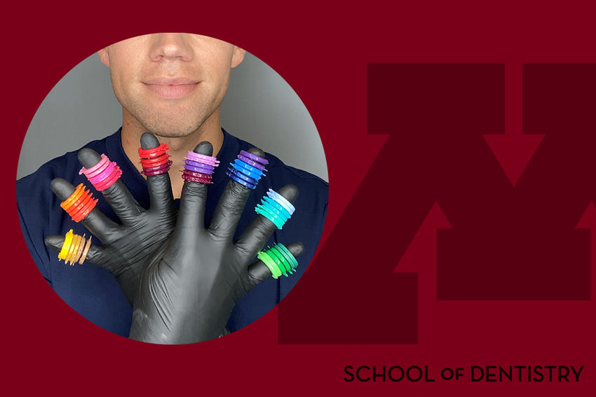 Photo of Grant Collins holding up braces rubber bands of various colors on each gloved finger, on a School of Dentistry branded background