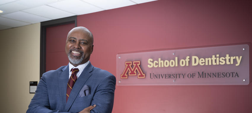 Dean Keith A Mays DDS MS PHD in front of a logo of the School of Dentistry