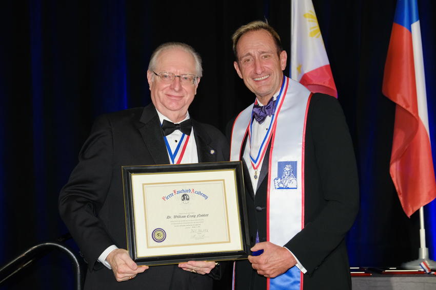 Two men holding award at induction ceremony.