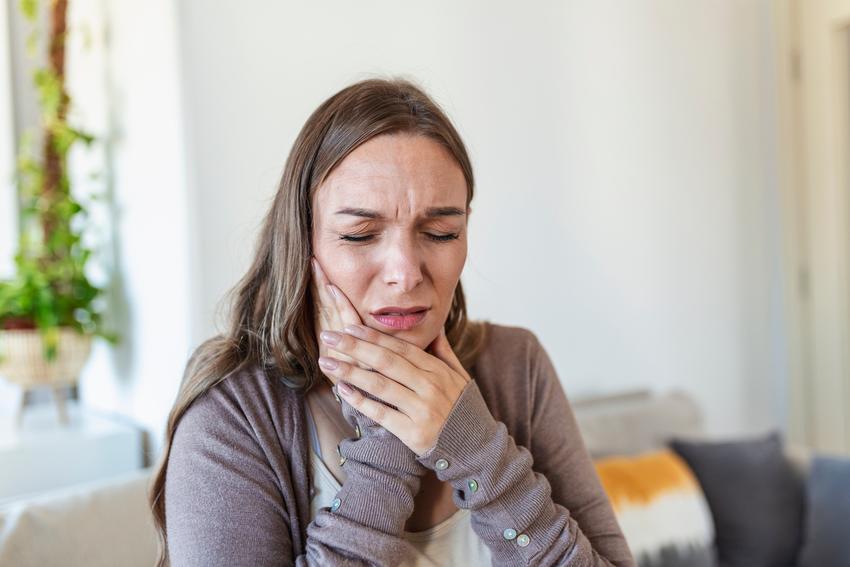 Woman holding jaw in pain.