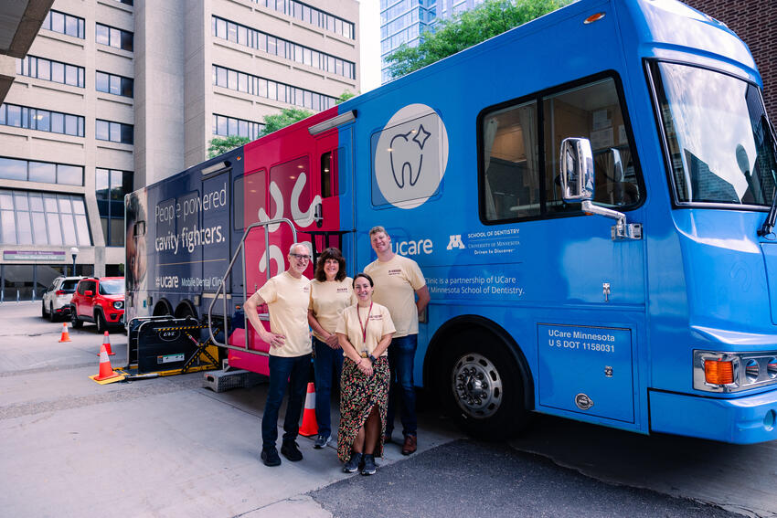 MDC parked outside Moos tower with 4 individuals standing in front of it.