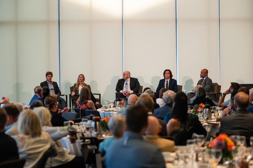 Four students talk onstage with Dean Mays in front of an audience