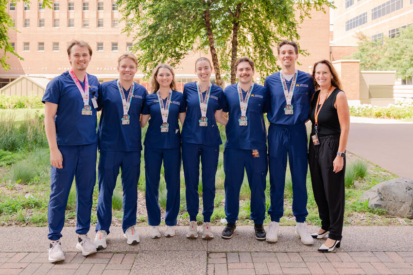 Marathon finishers pose in their scrubs with their metals