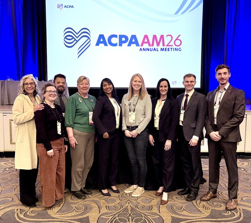 Members of the Cleft and Craniofacial Clinic pose in front of an APCA sign