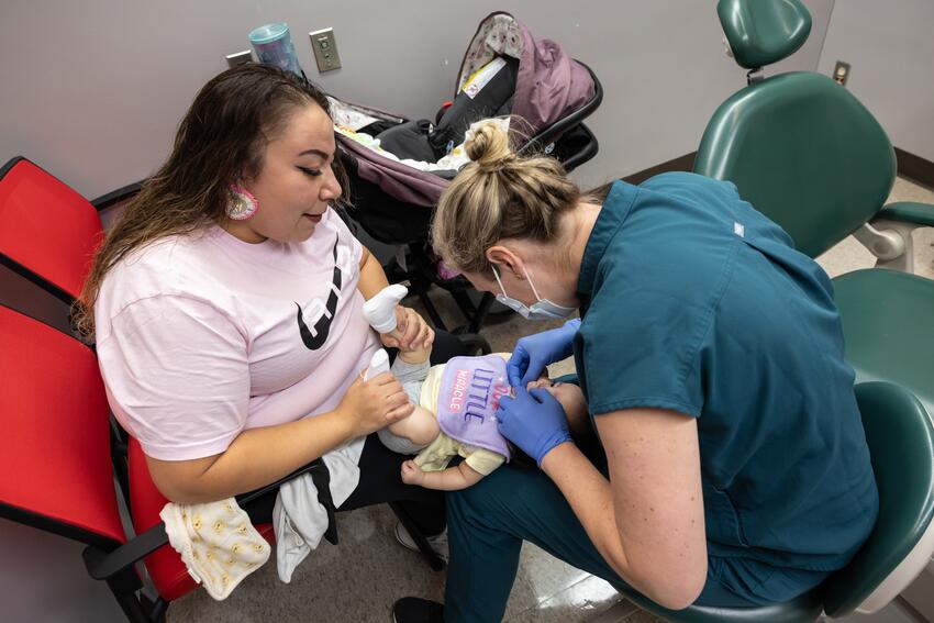 A provider examines an infant while her mother holds her in the knee-to-knee position