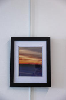A photograph of a sunset, with dark blue foreground and orange and gray streaked sky, blurred as if painted