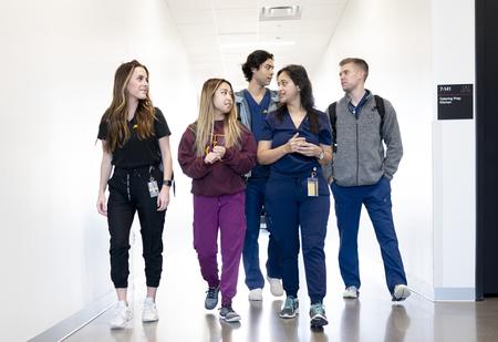 dental students walking down a hallway in scrubs and sweaters talking