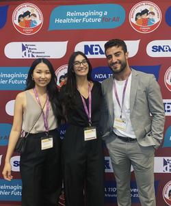 Three learners pose in front of a banner at SNDA