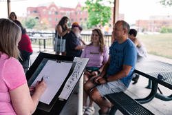 Two people pose for a caricature drawing