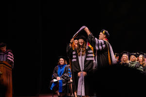 A graduate smiles while receiving her hood