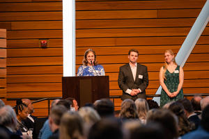 Pfahning speaks at a podium while two others stand beside her
