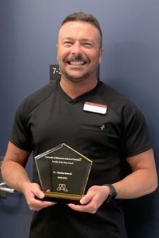 Charles Seawell wearing black scrubs and holding a glass trophy